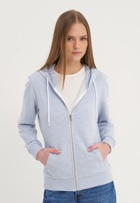 Sudadera con cremallera de color azul claro, hecha de tela suave, que cuenta con una capucha, cordones, dos bolsillos frontales y puños y dobladillo acanalados.