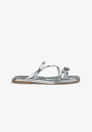 Zilverkleurige metalen sandalen met kruislings straps en een decoratieve accent bij de teen. Platte zool met een lichtbruine rand. Gladde textuur.