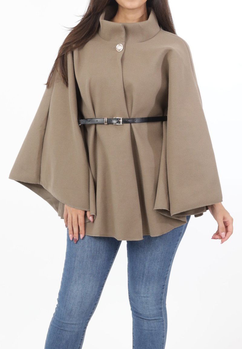 Brun kappa i cape-stil gjord av mjukt tyg, med en hög krage, en enda dekorativ knapp och ett svart bälte som framhäver midjan.