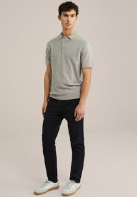 Polo shirt gri deschis, cu dungi, cu mâneci scurte, asortat cu pantaloni slim-fit negri și adidași albi cu tălpi bej. Design casual, texturat.