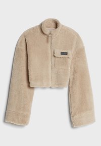 Przycięta, beżowa kurtka z polaru z wysokim kołnierzem, długimi rękawami i frontowym zamkiem błyskawicznym. Posiada naszywaną kieszeń z logo.