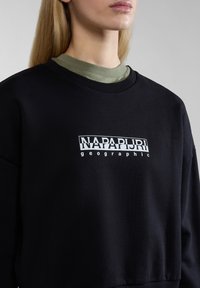 Sudadera negra con un logotipo gráfico blanco que dice "NAPAPIJRI geographic." Incluye un cuello de canalé y una textura suave.