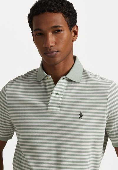 Tricou polo cu dungi verzi și albe, cu guler, având un logo mic pe pieptul stâng și două butoane la gât.