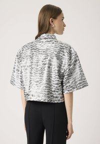Ezüst és fekete absztrakt mintázatú, rövid ujjú cropped ing, galléros nyakkal és sima textúrával. Hátulnézet látható.