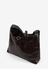 Bolso de cuero marrón con estampado de cocodrilo y forma suave. Presenta una parte superior redondeada, cierre interior y detalles de hardware en color dorado.