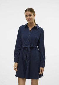 Robe bleu marine à manches longues avec boutons, ceinturée à la taille, et un col, avec un tissu texturé et des boutons métalliques.
