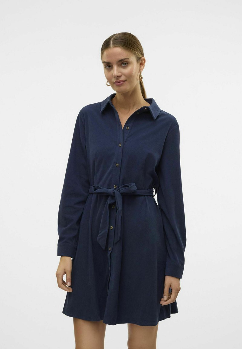 Robe bleu marine à manches longues avec boutons, ceinturée à la taille, et un col, avec un tissu texturé et des boutons métalliques.