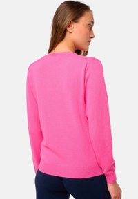 Pull en tricot rose avec des manches longues et un col rond. Présente des poignets et un ourlet côtelés. Texture lisse, matériau léger.