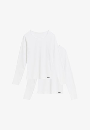 Dwie proste białe koszulki z długim rękawem i okrągłym dekoltem, nałożone jedna na drugą, z małymi czarnymi prostokątnymi metkami marki przy dolnym brzegu.