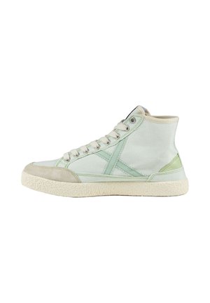Zapatilla de caña alta en tonos verde claro y crema con cordones blancos y suela de goma texturizada, vista de lado sobre fondo blanco.
