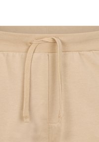 I pantaloni della tuta beige presentano una vita con cordoncino, una texture liscia, una cintura elastica e tasche laterali. Dettagli cuciti lungo le cuciture.