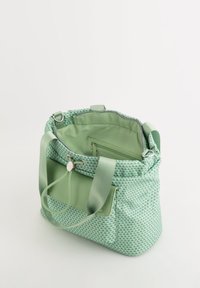 Green patterned tote bag with a textured exterior, soft fabric interior, dual handles, an inner zip pocket, and a cinching closure.