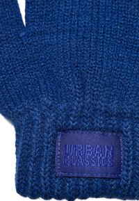 Zilā adīta cimda, kas izceļas ar teksturētu audumu. Iekļauta taisnstūra purpura birka ar uzspiedumu "URBAN CLASSICS". Atvērtie pirksti.