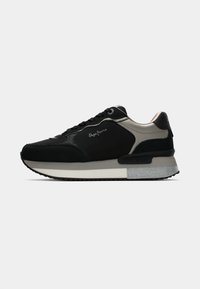 Svart sneaker med semsket og lærdetaljer, med en teksturert grå såle, grå aksenter og et rundt tådesign.