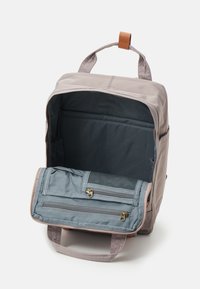 Gray canvas backpack with a structured design, leather handle, and a spacious interior featuring a blue lining and multiple zippered pockets.
