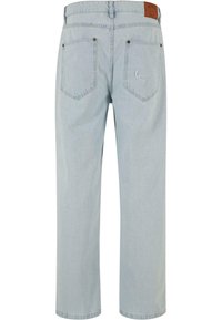 Heled sinised teksad omavad sirget lõiget, kaks tagumist taskut nähtava õmblusega ja pruuni nahast vöötaga silti.