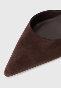 Chaussure plate en daim marron foncé à bout pointu avec doublure intérieure lisse sur fond gris clair.