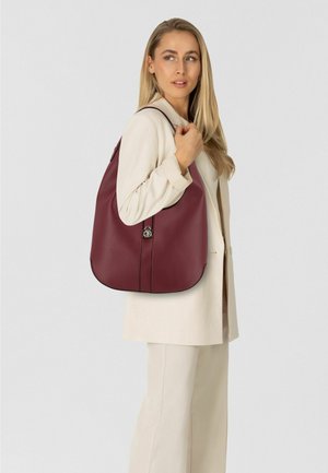 Sac à bandoulière en cuir bordeaux avec une texture lisse, une forme incurvée et des coutures discrètes ; doté d'un détail en métal argenté pour la fermeture.