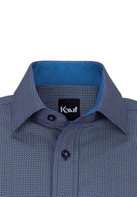 Camicia a motivo navy con colletto interno blu. Presenta un design geometrico, chiusura con bottoni e una consistenza del tessuto che appare liscia.