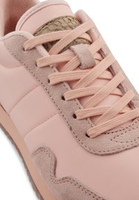 Jasnoróżowe sneakersy wykonane z gładkiej skóry i teksturowanego zamszu, z dopasowanymi sznurowadłami oraz akcentem w wzór wężowej skóry na języku.