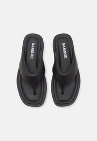Sorte thong sandaler med en glat læderoverdel, kontureret fodseng og kontrasterende syninger. Mærket "SAMSØE" er vist på indersålen.