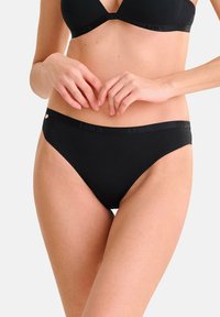 Culotte de bikini en coton noir avec une texture lisse, dotée d'une taille douce embossée avec "Lisca". Conçue pour le confort et l'ajustement.