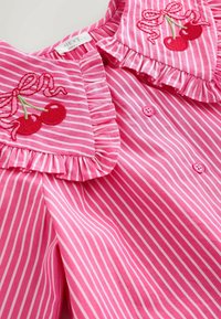 Roza prugasta bluza s naboranim ovratnikom i rukavima, vezene trešnje s mašnama i ružičasti gumbi. Mekana pamuk tekstura.