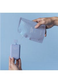 Lichtpaarse handdesinfectieflacon met een pomp, vastgehouden naast een bijpassende navulpouch. Beide tonen "Morning Glory" in witte tekst.