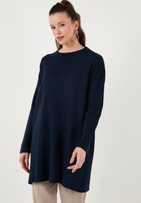 Sötétkék bordás pulóver hosszú ujjakkal és kerek nyakkivágással, laza fazonnal és puha tapintással.