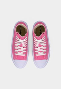 Ζευγάρι ροζ υφασμάτινα αθλητικά παπούτσια με λευκά λαστιχένια καλύμματα στα δάχτυλα και κορδόνια, σε θέα από πάνω πάνω σε λευκό φόντο.