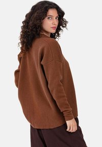 Pull surdimensionné marron à manches longues, en maille texturée, avec un ourlet arrondi. Présente une coupe légèrement tombante aux épaules.