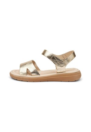 Sandalia plana con tiras de cuero metálico dorado y suela acolchada beige con suela exterior de goma marrón texturizada, diseño abierto en el tobillo y los dedos.