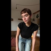 Fekete, rövid ujjú crop top és világoskék, magas derekú farmernadrág. Simaság, egyszerű dizájn, fa elemekkel díszített szobában áll.