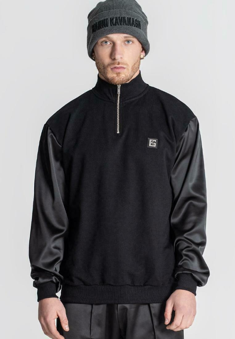 Černý hybridní svetr s límcem na zip, vyrobený z texturované látky a hladkých saténových rukávů. Obsahuje malé označení značky.