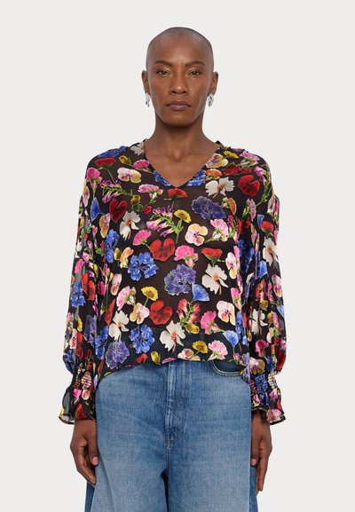 Black floral blouse featuring a mix of brightly colored flowers, V-neckline, and billowy sleeves with elastic cuffs, paired with blue denim jeans.