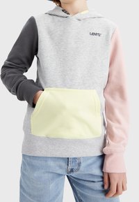 Hoodie Levi's con corpo grigio, maniche nere e rosa, e tasca gialla. Presenta un cappuccio con stringa e polsini a coste.