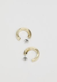 Złote kolczyki w kształcie obręczy o gładkiej, błyszczącej powierzchni oraz zaokrąglonym kształcie. Zapięcie z tyłu posiada srebrny stift i zatyczkę.