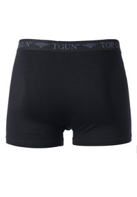 Mustat bokserit, jotka on valmistettu pehmeästä kankaasta, ja joissa on joustava vyötärönauha, jossa on harmaalla "TGUN" ja "TOP GUN" -brändäys.