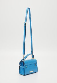 Blue crocodile-patterned shoulder bag with a structured design, featuring a top handle, adjustable strap, and gold accents.