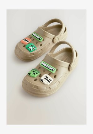 Bež plastični kakovosti oklji z odprtinami za zrak in dekoracijami v zelenih, oranžnih in belih temah likov. Imajo tudi zadaj trak za boljšo prileganje.