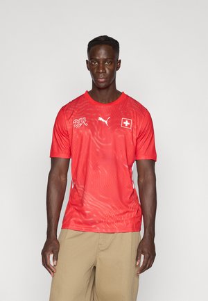 Piros sportos póló légáteresztő anyagból, texturált mintázattal, Puma logóval és svájci zászló jelvénnyel. Rövid ujjú, kerek nyakú.