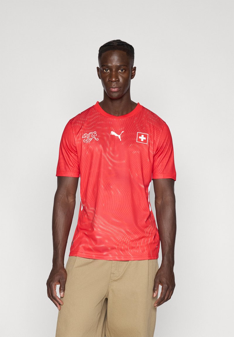 Piros sportos póló légáteresztő anyagból, texturált mintázattal, Puma logóval és svájci zászló jelvénnyel. Rövid ujjú, kerek nyakú.