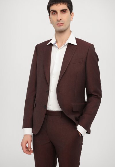 Costume bordeaux avec une coupe slim, veste à un seul bouton et pantalon à poches plates. Chemise blanche avec un col à motifs. Tissu texturé, design sur mesure.