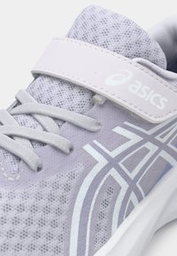 Αθλητικό παπούτσι σε ανοιχτό μωβ χρώμα με πλέγμα στο επάνω μέρος, επίπεδα κορδόνια και ιμάντα με βέλκρο. Διαθέτει λευκό λογότυπο και σχεδιαστική λεπτομέρεια στο πλάι.