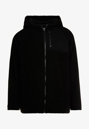 Sort fleecetrøje med lynlås foran, en ensfarvet sort brystlomme og en blød tekstureret finish. Har hætte og raglanærmer.