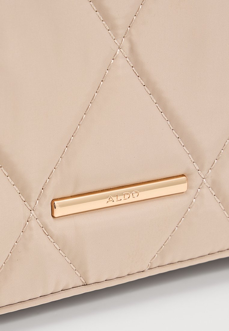 Sac beige matelassé avec une texture lisse et une plaque en métal doré avec "ALDO" en relief. Couture en motif diamant remarquable.