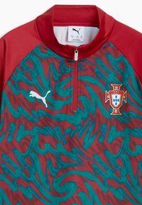 Haut d'entraînement de football du Portugal rouge et bleu sarcelle avec zip quart, logo Puma sur la poitrine gauche et écusson de l'équipe nationale du Portugal sur la poitrine droite.