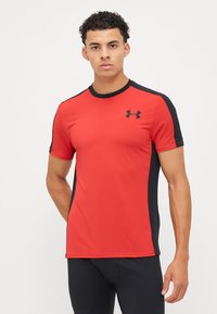 Rød atletisk t-skjorte med svarte sidestriper, korte ermer, ensfarget design, laget av pustende materiale, har Under Armour-logo på brystet.