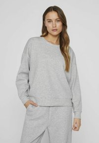 Šviesiai pilkas džemperis su laisvu kirpimu, apvalia kaklo iškirpte ir puskraštinėmis rankovėmis. Pirmoje pusėje yra subtilus išsiuvinėtas tekstas.