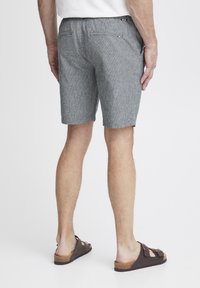 Grå og hvite stripete shorts med en avslappet passform, med to baklommer og elastisk midje, kombinert med brune sandaler.